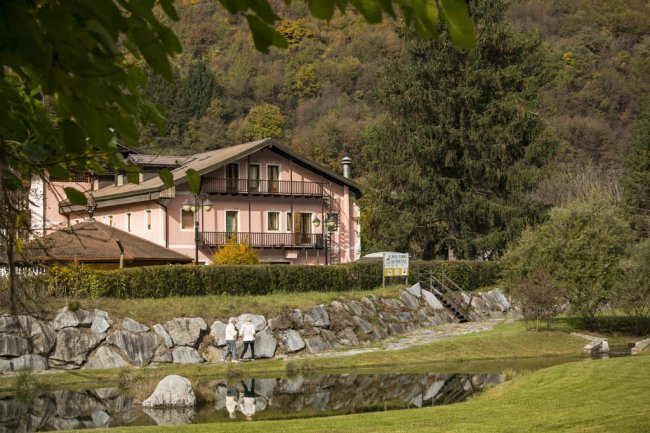 Edificio rosa con giardino e stagno riflettente.