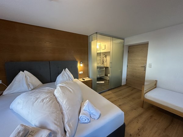 Interno di una camera d'albergo con letto matrimoniale e bagno a vista.