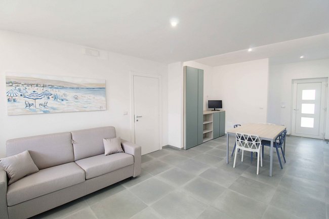 Soggiorno luminoso con divano e tavolo da pranzo.