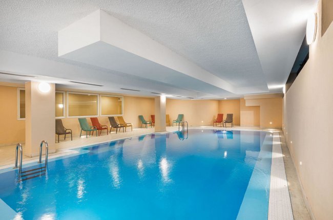 Piscina interna con lettini colorati.