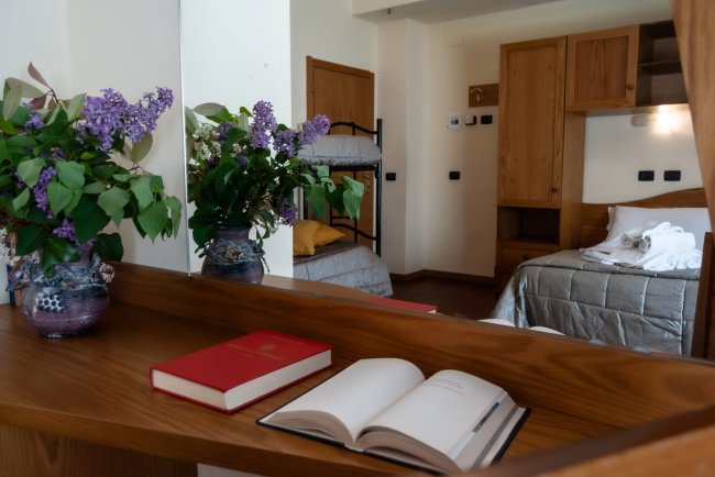 Specchio con libro aperto e vaso di fiori.