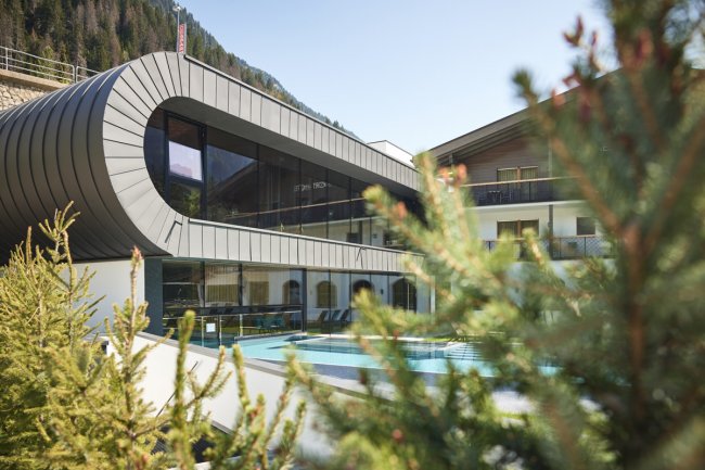 Struttura moderna con piscina e pini in primo piano.