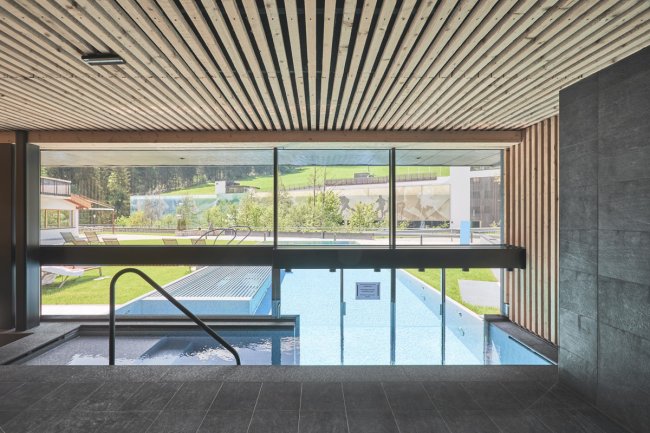 Piscina interna con vista su una piscina esterna e giardino.