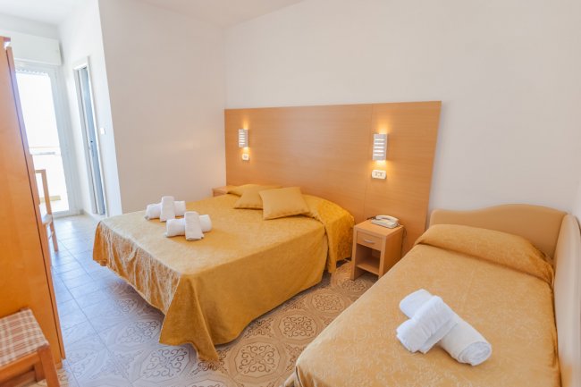 Camera con letto matrimoniale, singolo e asciugamani.