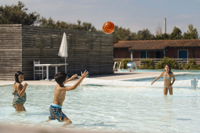 Tre bambini giocano a palla in una piscina all'aperto.