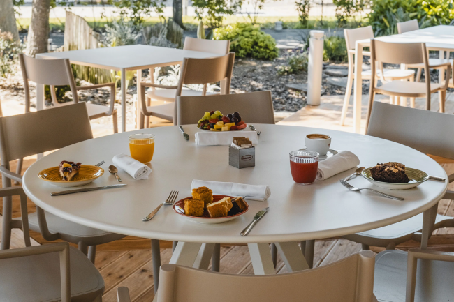 Tavolo all’aperto con colazione composta da succhi, dolci e frutta.