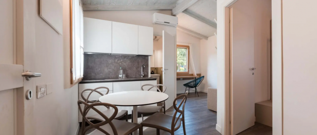 Cucina moderna con tavolo rotondo, sedie e interni luminosi.
