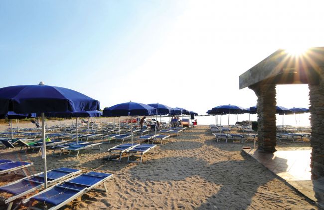 Spiaggia con ombrelloni blu e lettini.