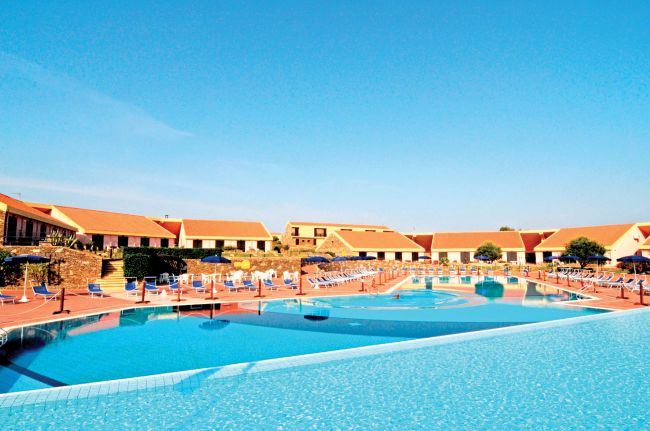 Piscina all'aperto con sdraio e ombrelloni.