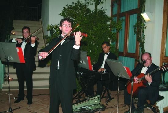 Gruppo musicale con violini e chitarra suona sul palco all'aperto.