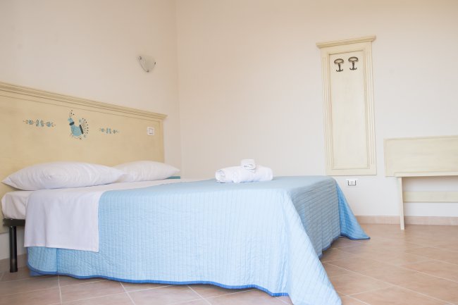 Una camera con letto matrimoniale e biancheria blu chiaro.