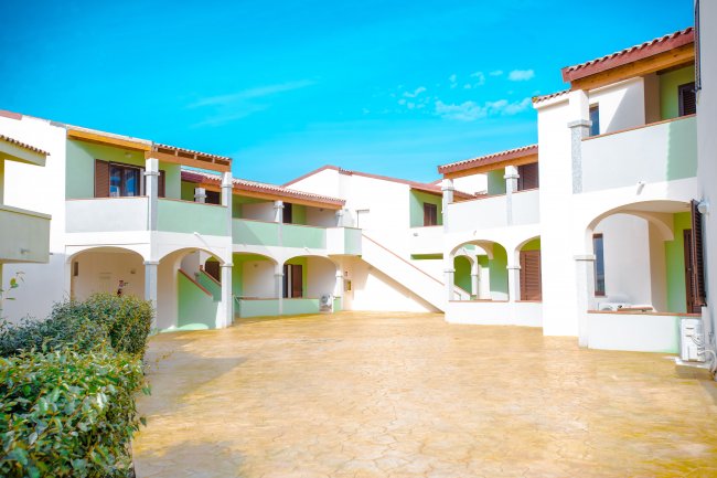 Cortile di un complesso residenziale con arcate e scale esterne.