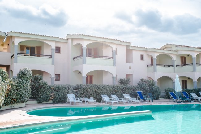 Complesso residenziale con balconi e piscina con lettini.