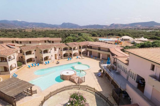 Complesso con piscina e sdraio, vista sulle montagne.