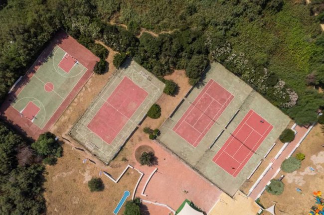 Veduta dall'alto di campi sportivi tra gli alberi.