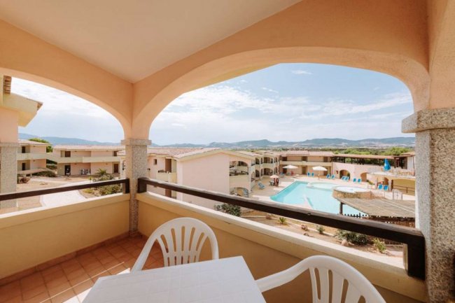 Balcone con vista su una piscina e colline.