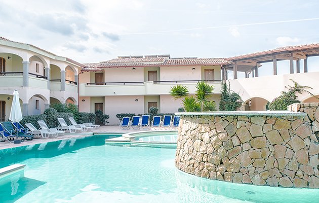 Piscina con sedie a sdraio e edificio sullo sfondo.