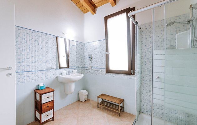 Bagno con doccia in vetro e finestra luminosa.