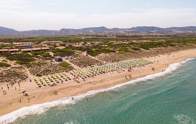 Spiaggia sabbiosa con file di ombrelloni gialli.