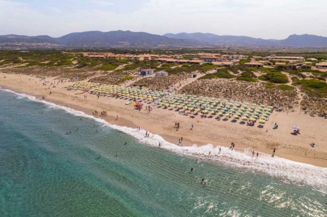 Spiaggia affollata vista dall'alto con ombrelloni colorati.