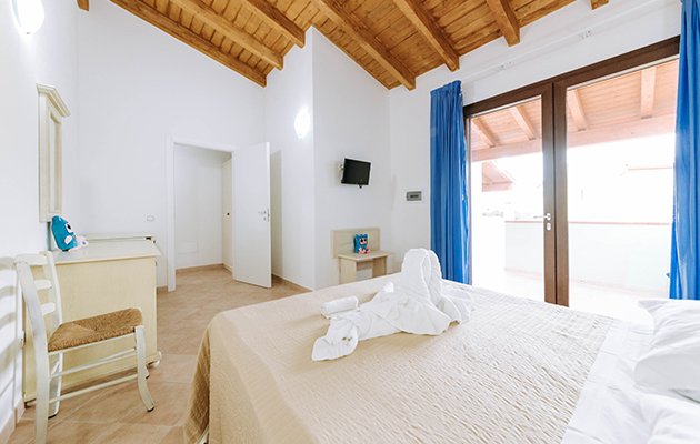 Camera da letto con soffitto in legno e finestra ampia.