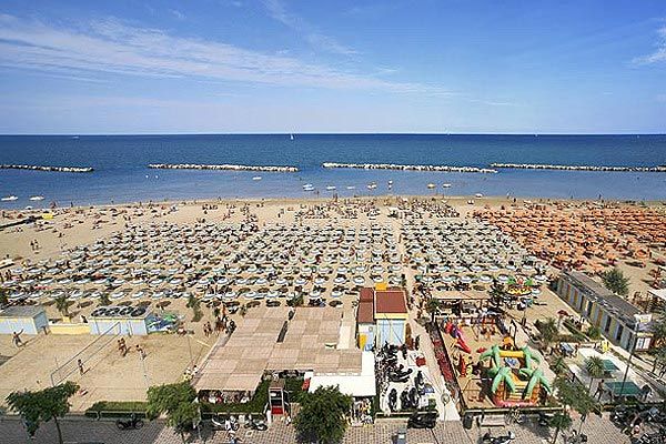Spiaggia affollata con file di ombrelloni e mare sullo sfondo.