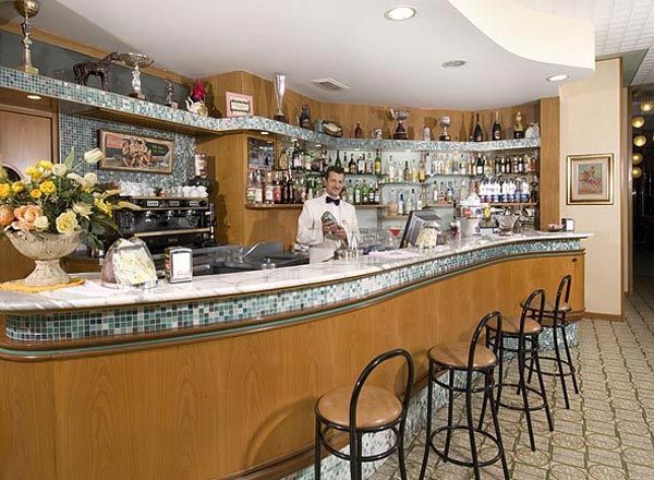 Un bar con bancone curvo, barista in divisa e vari scaffali di bottiglie.