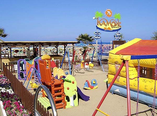 Area giochi colorata per bambini sulla spiaggia, con scivoli e gonfiabili.