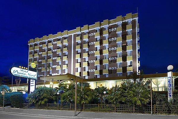 Edificio di un hotel illuminato di notte con balconi sporgenti.