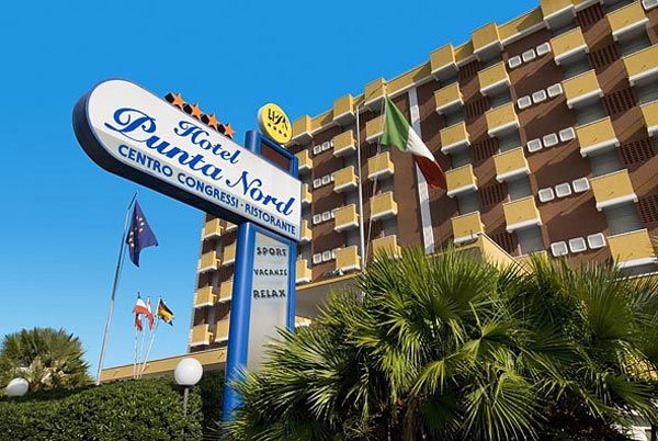 Insegna dell'Hotel Punta Nord con varie bandiere e palme.