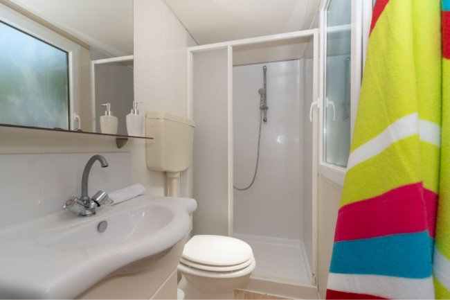 Bagno moderno con doccia, lavandino e asciugamano colorato.