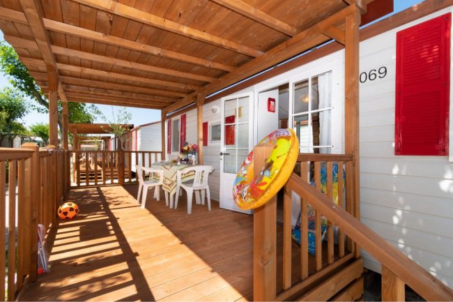 Veranda con tavolo, sedie e salvagente appeso alla porta.