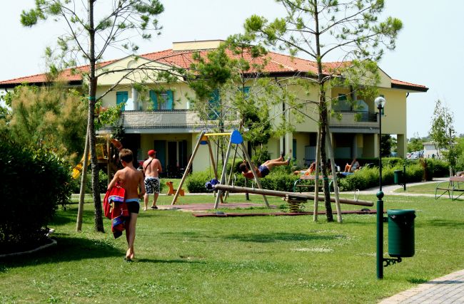 Giardino con prato, un edificio e alcune persone vicino a un'altalena.