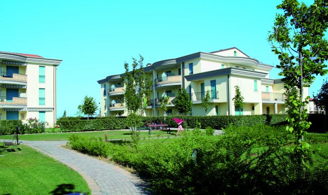 Complesso residenziale con giardini e sentiero pedonale.