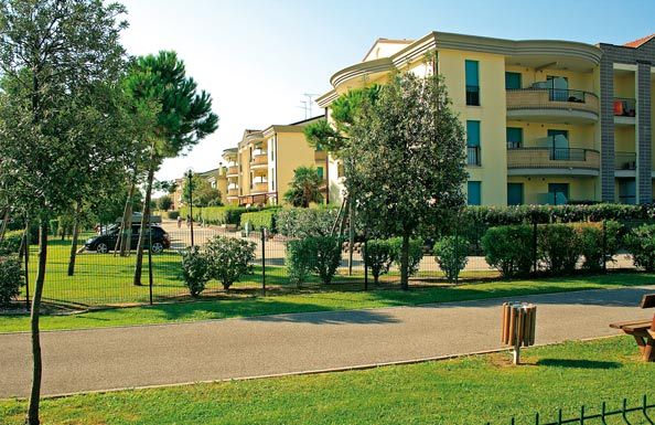 Edifici moderni con balconi circondati da alberi e siepi.