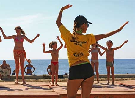 Gruppo fa esercizi con istruttrice sulla spiaggia.