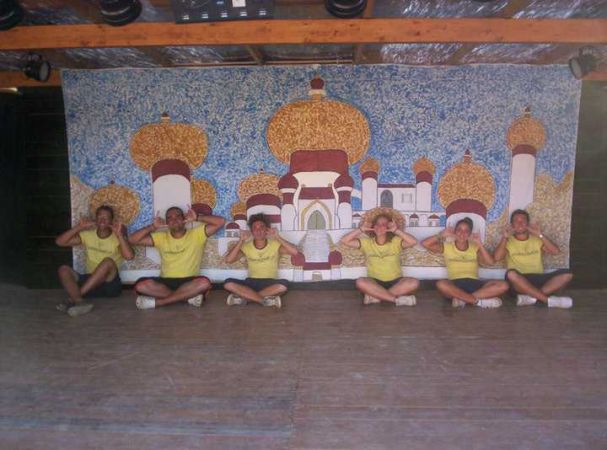 Sette persone sedute con maglie gialle su un palco.