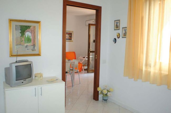 Corridoio con TV su mobile bianco, porta aperta verso soggiorno.