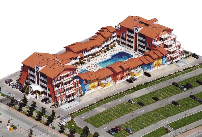 Complesso residenziale con tetti rossi, piscina interna e parcheggi.