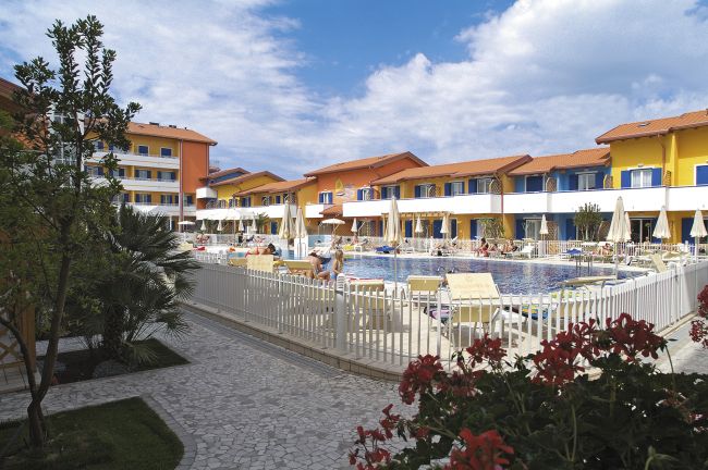 Complesso colorato con piscina e sedie a sdraio.