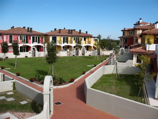 Complesso residenziale con edifici colorati e giardino centrale.