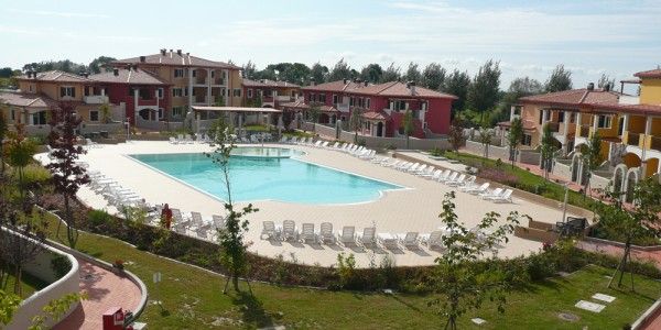 Complesso residenziale con piscina centrale e numerose sedie a sdraio.