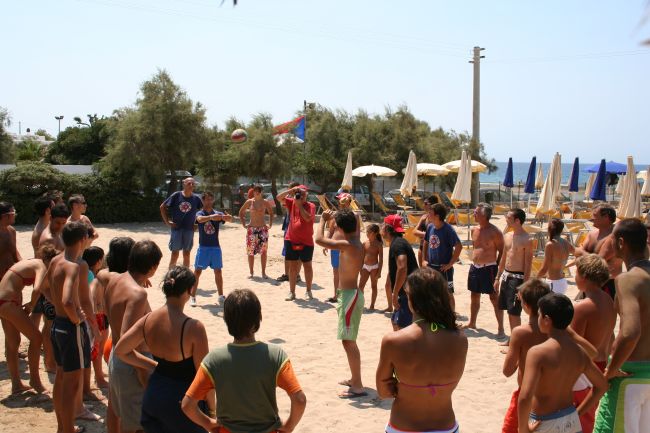 Persone in cerchio giocano a palla sulla spiaggia.