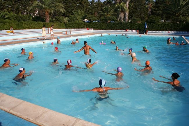 Persone nuotano in una grande piscina all'aperto.