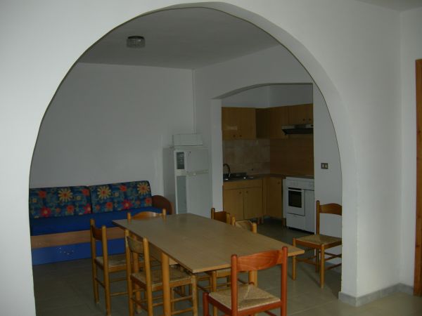 Sala da pranzo con tavolo, sedie e cucina ad arco.