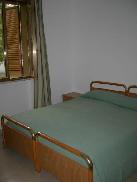 Camera da letto con letto matrimoniale e finestra con tende.