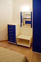 Camera moderna con mobili blu e bianchi, specchio e letto.