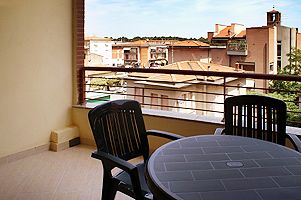 Balcone con tavolo e sedie nere, vista su tetti e edifici circostanti.