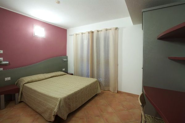 Stanza d'albergo moderna con letto matrimoniale, pareti bicolore e tende chiare.