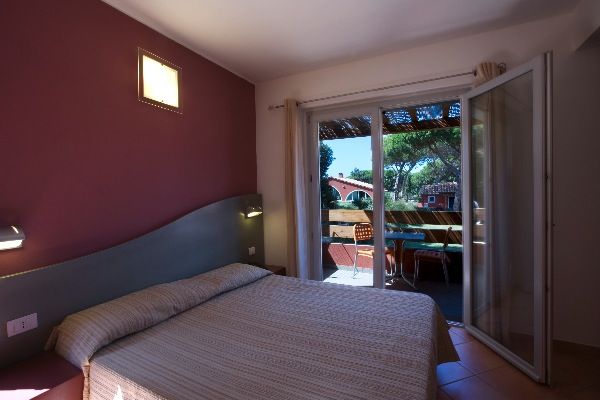 Letto matrimoniale vicino a porte scorrevoli, terrazza con tavolo. Parete viola.